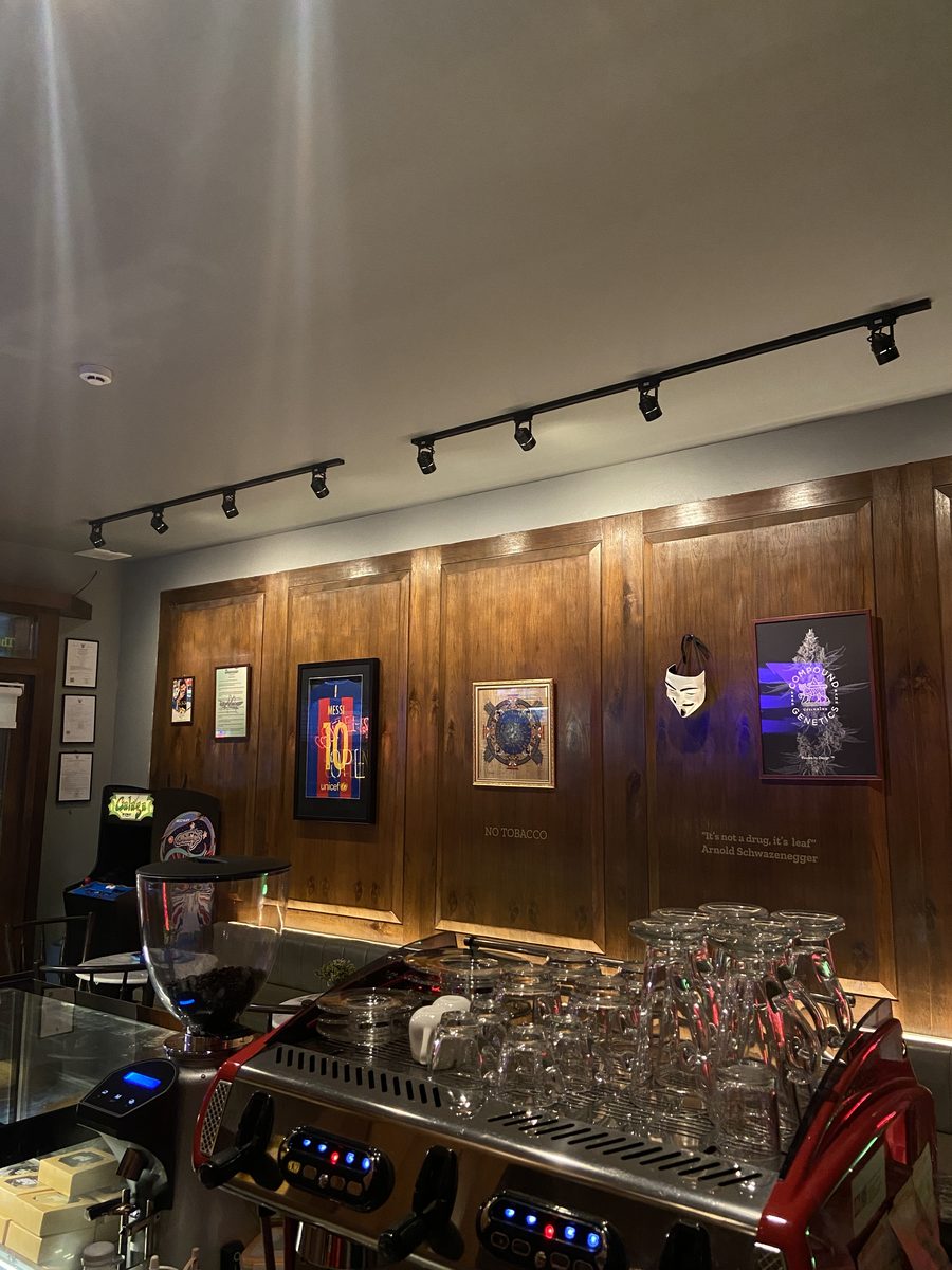 Espresso machine and glassware at the coffee bar, framed art on warm wood walls