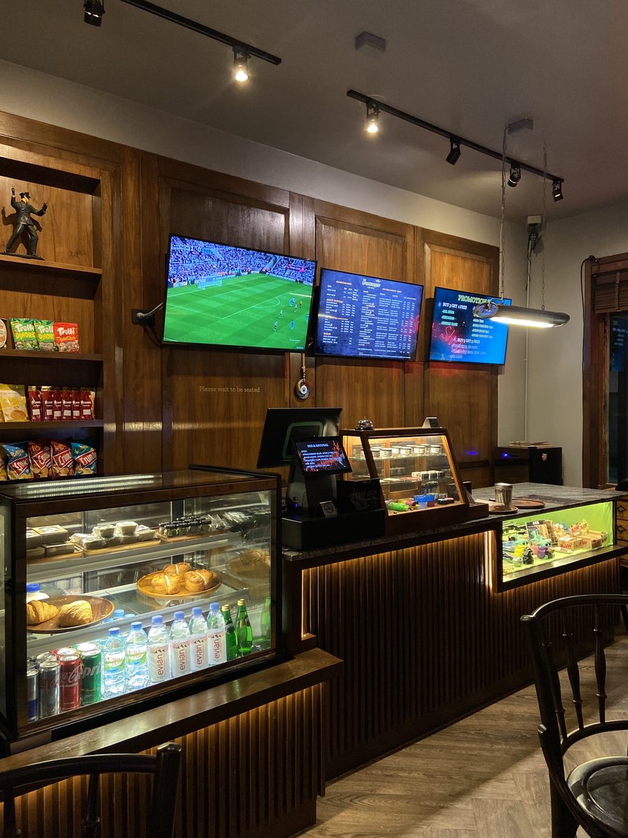 Glass display counter with snacks and drinks, football on the TV screens above
