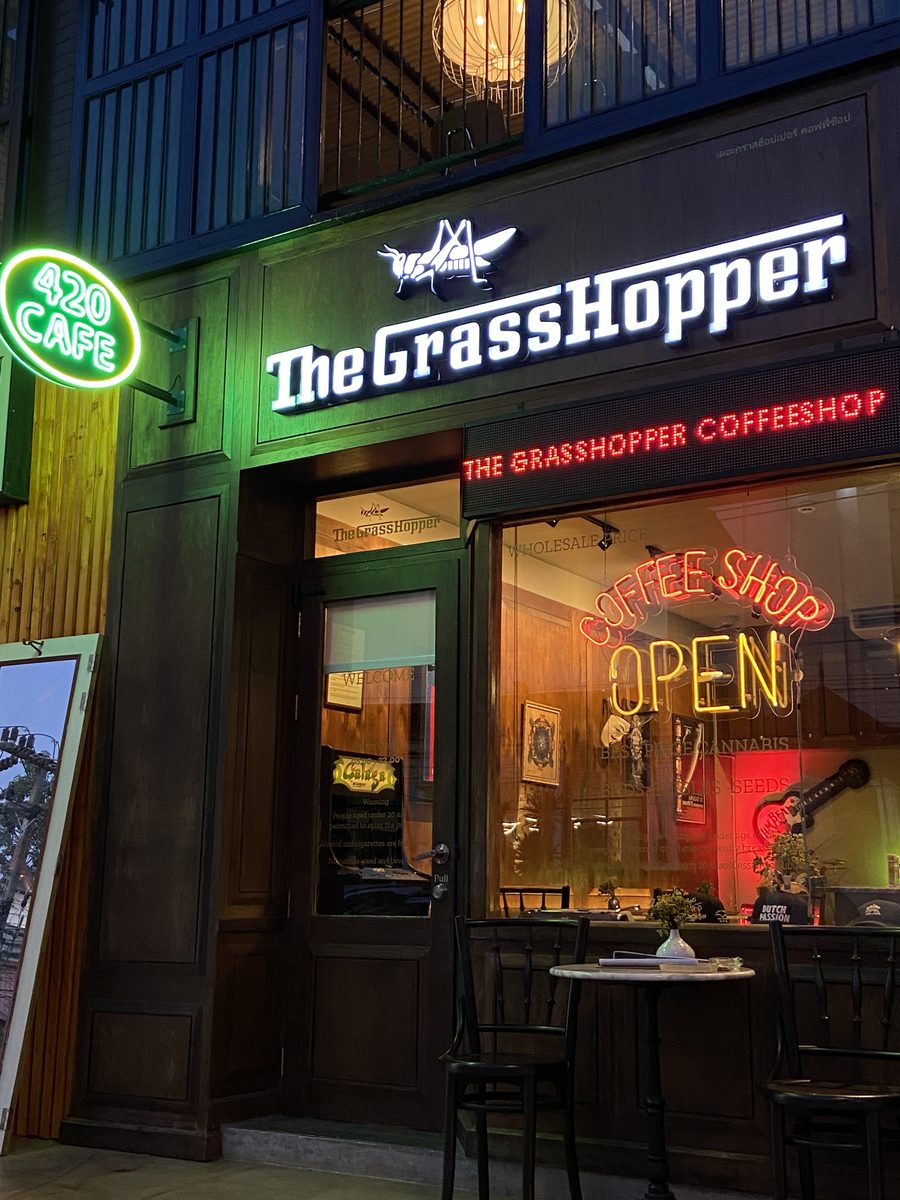 The Grasshopper shop front with green “420 Café” neon and The Grasshopper Coffeeshop sign